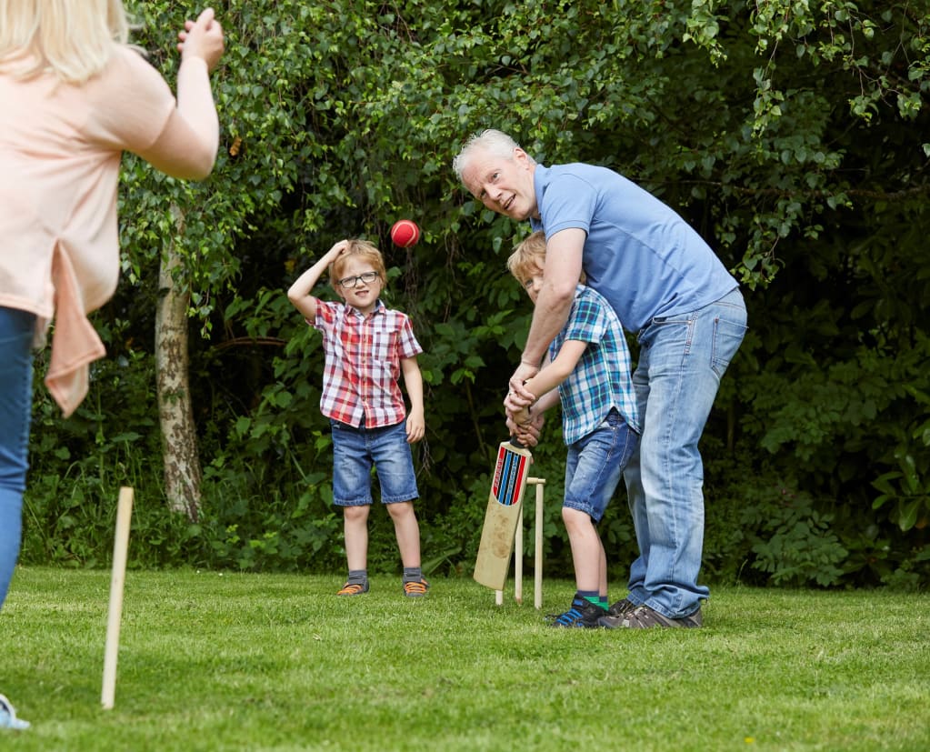 Children playing cricket with their parents